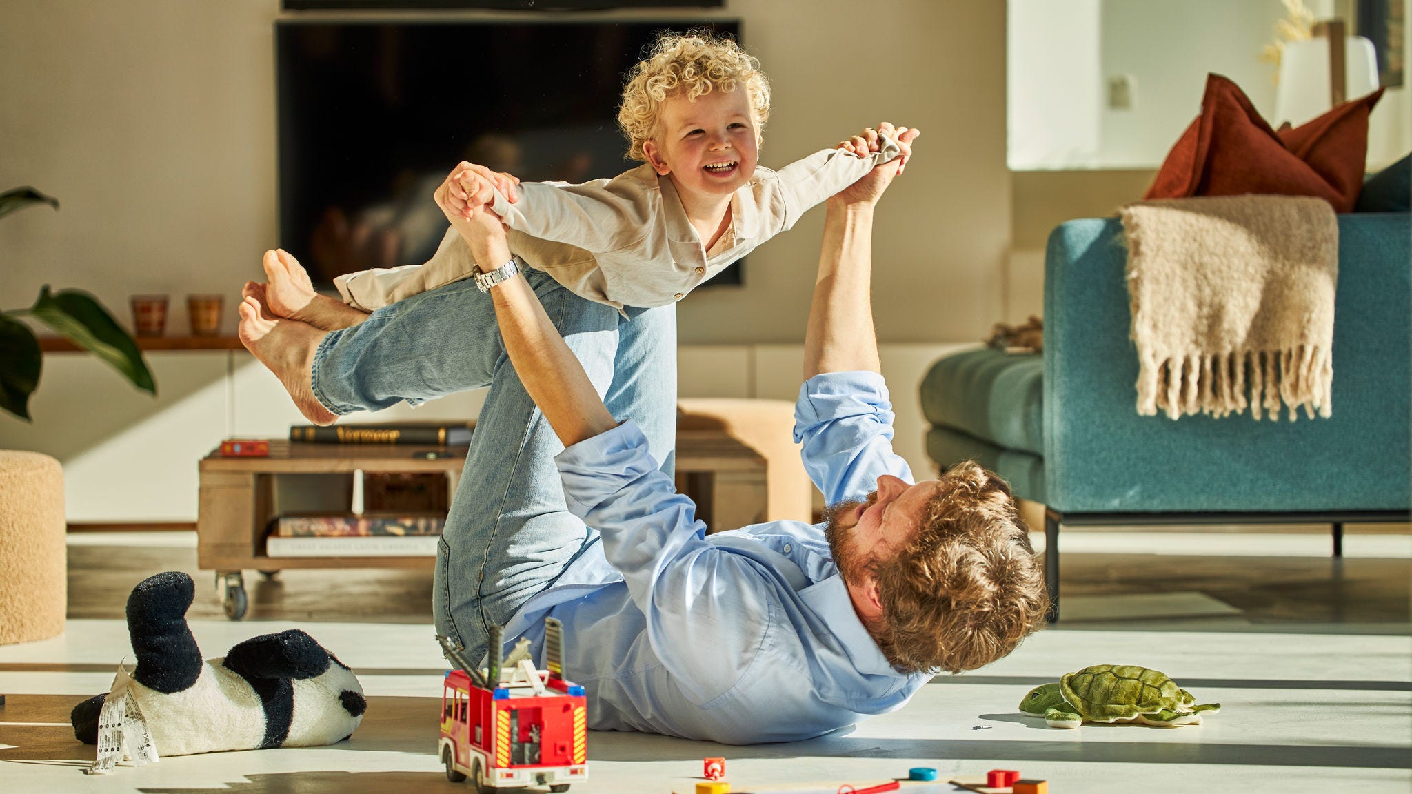 Otac i dijete veselo se igraju i uživaju u toplini podnog grijanja