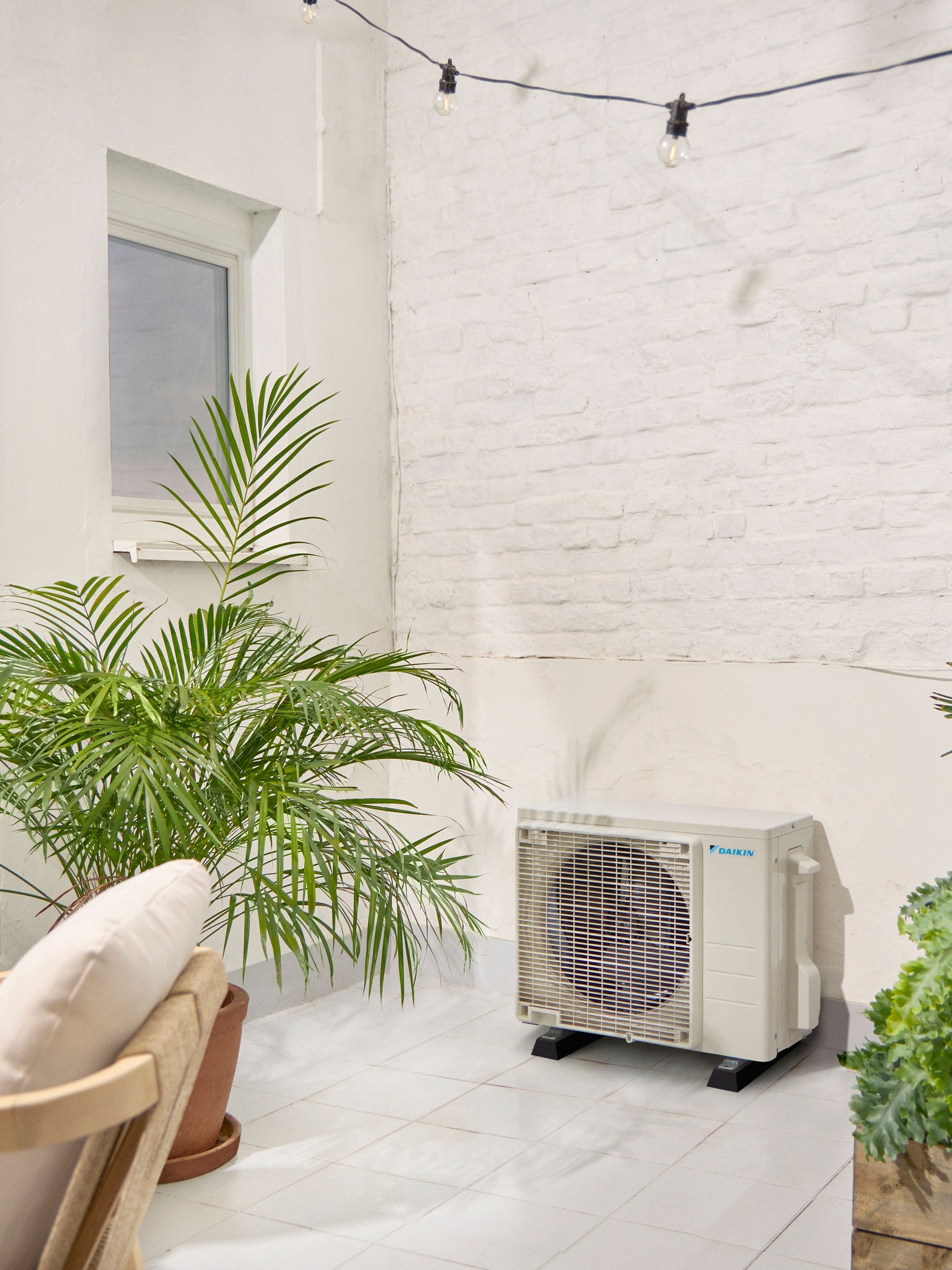 Daikin vanjska jedinica na bijeloj terasi s biljkom