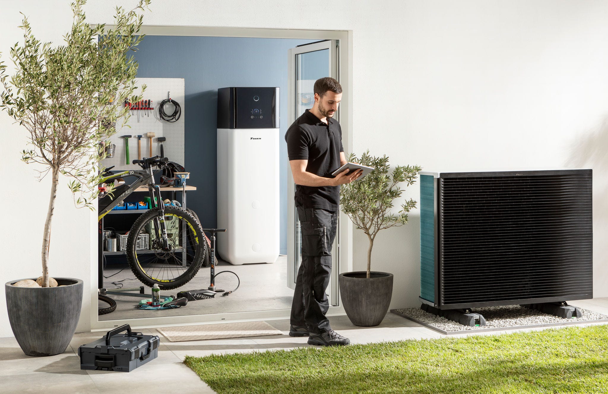 Instalater provjerava vanjsku jedinicu toplotne pumpe zrak-voda i spremnik tople vode