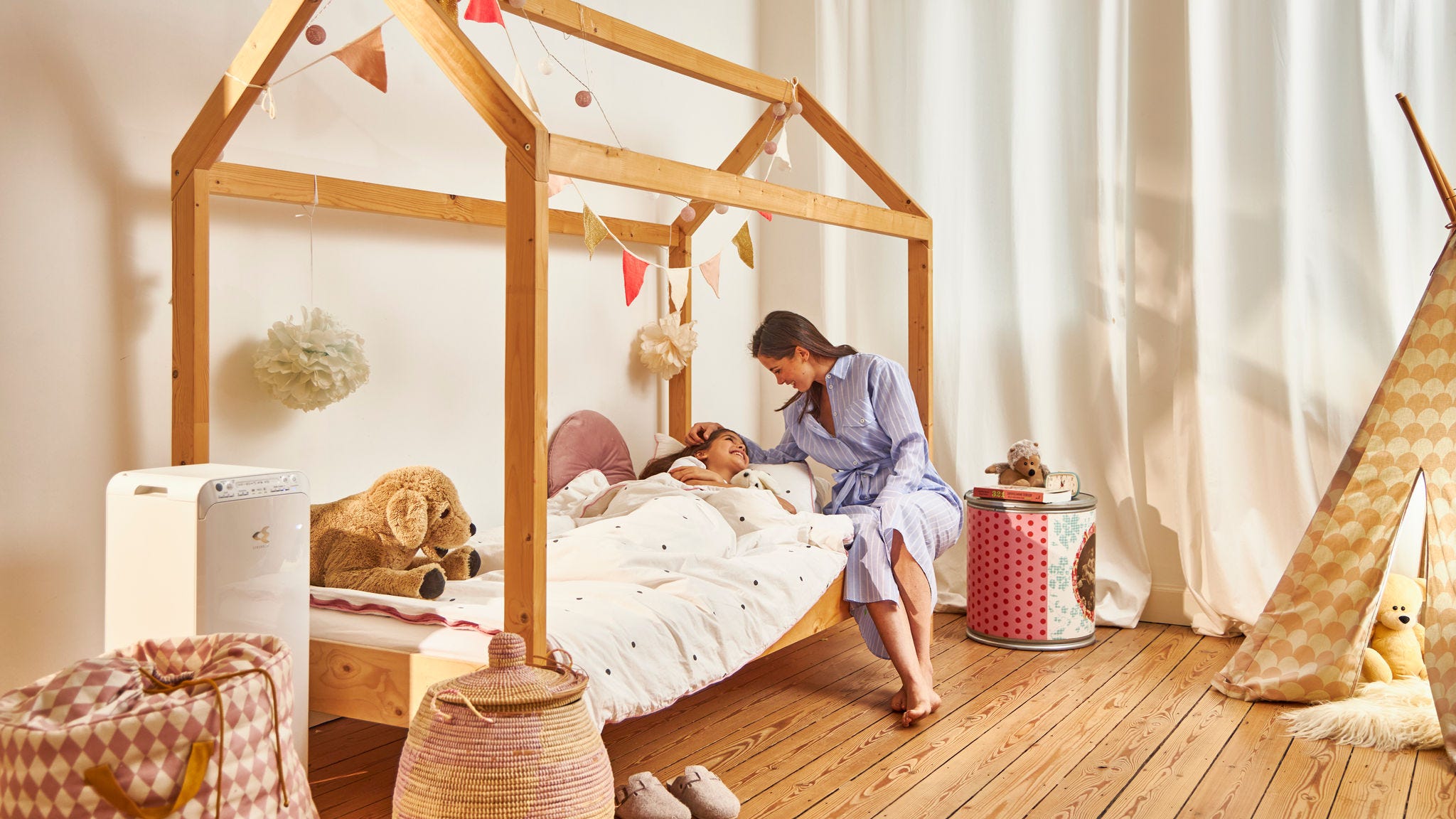 Majka polaže dijete u krevet u zdravom domu zahvaljujući Daikin pročistaču zraka u dječjoj sobi