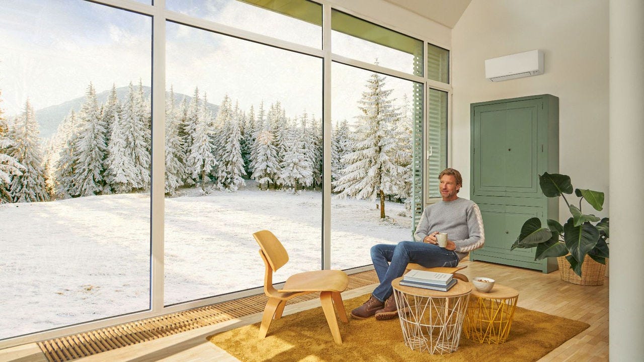 Muškarac sjedi na sofi i uživa u grijanju uz klima-uređaj