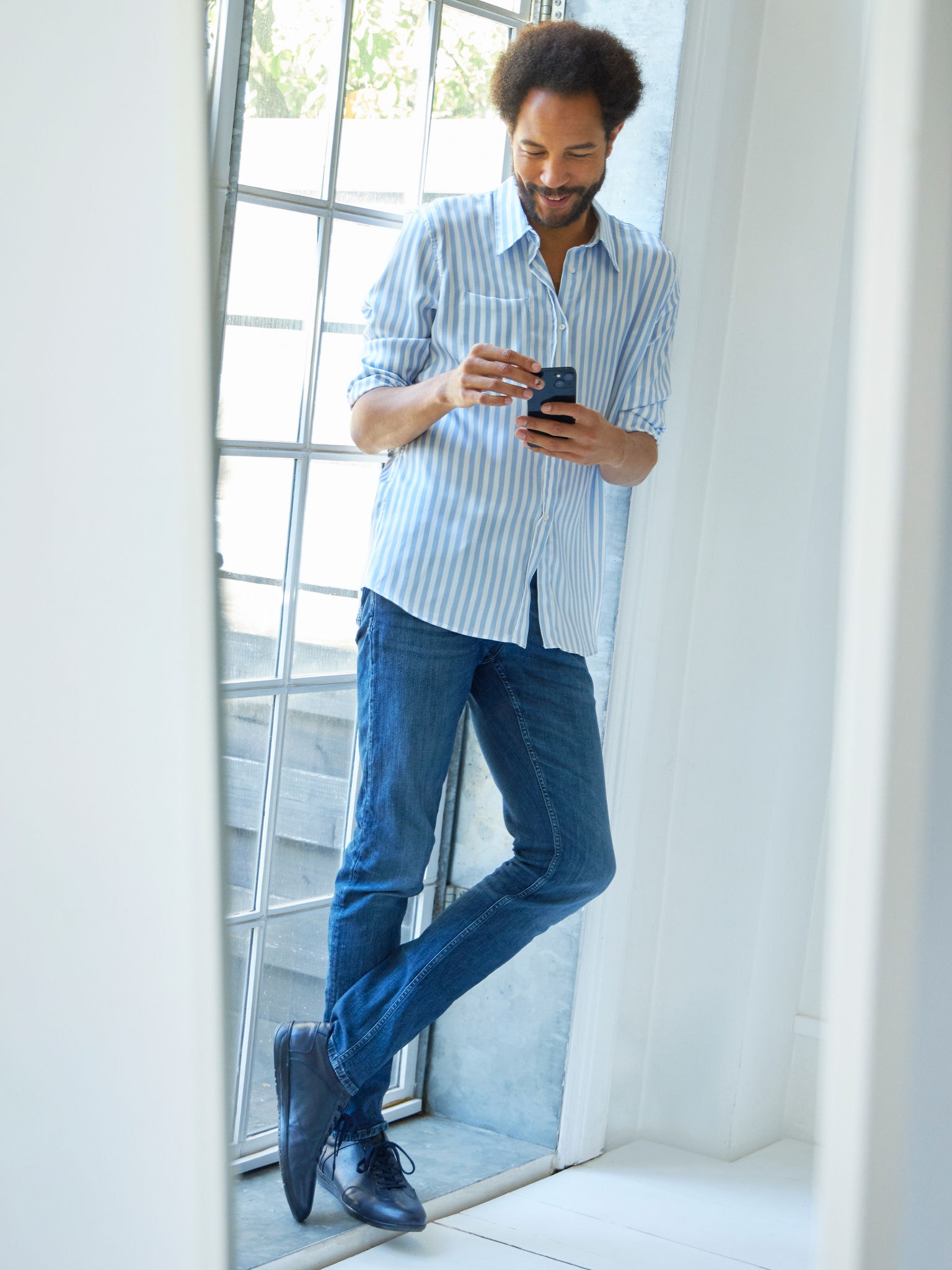 Muškarac koji stoji blizu prozora i istražuje klima-uređaje u Virtuelnom Experience Centru na pametnom telefonu