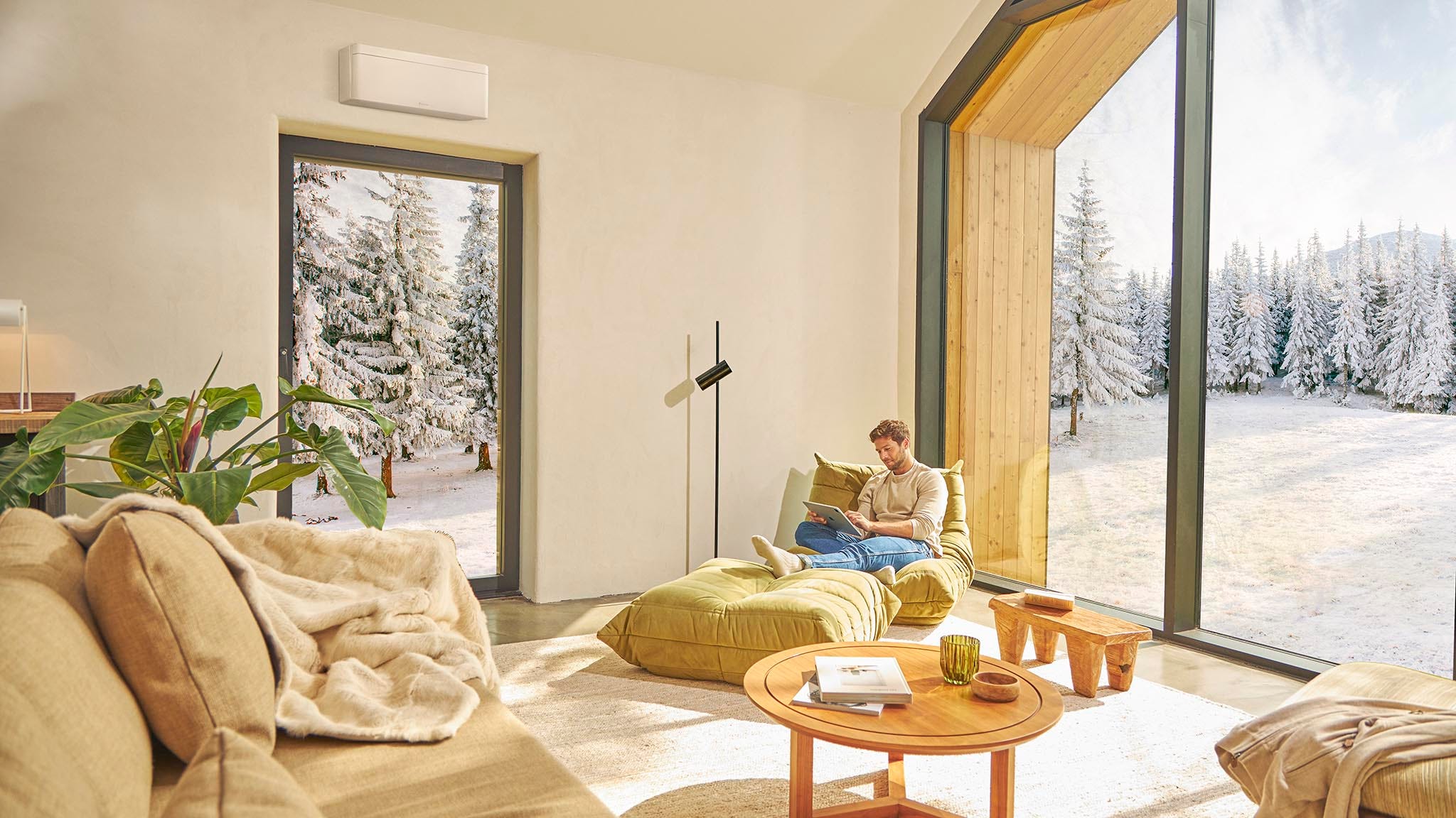 Muškarac sjedi na sofi i uživa u grijanju uz klima-uređaj