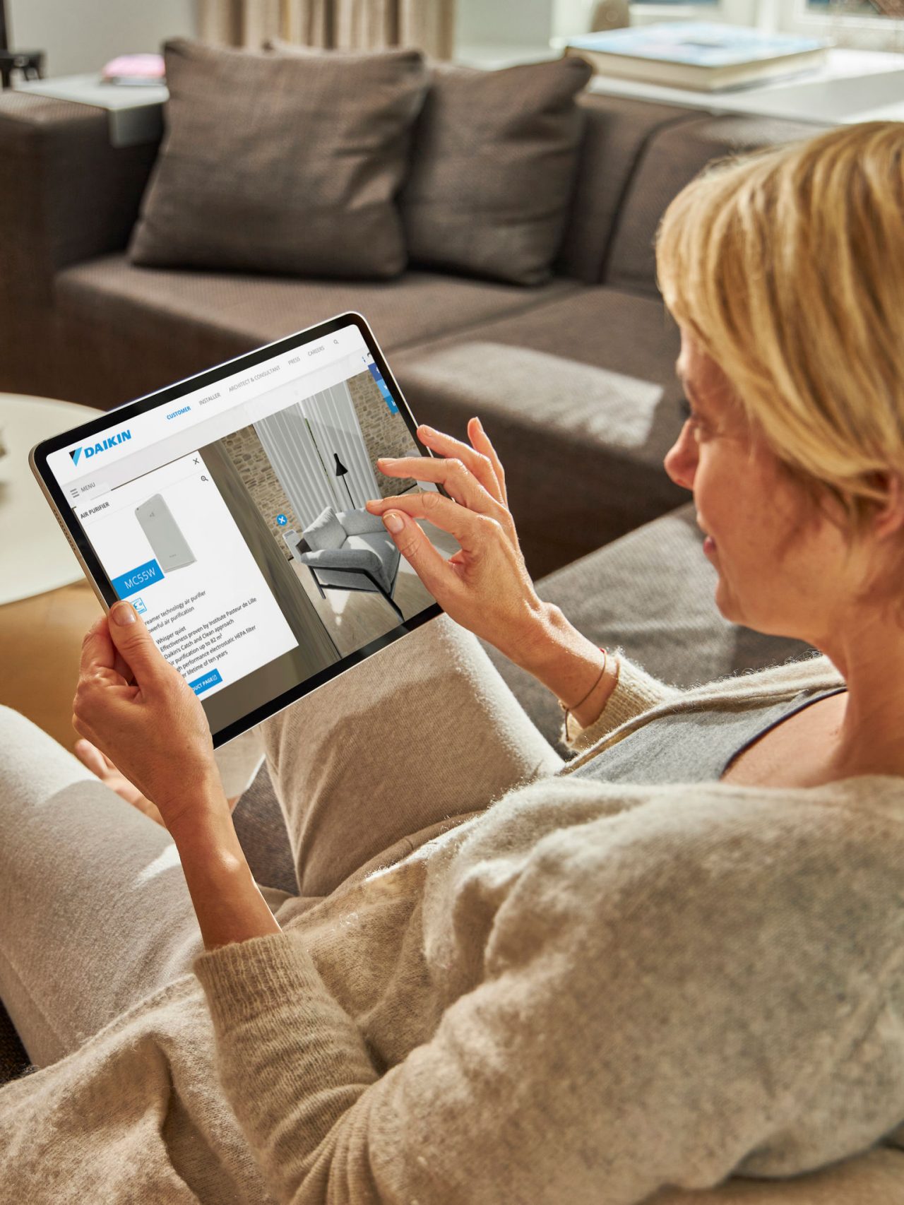 Žena sjedi na sofi i gleda klima uređaje u centru za virtualno iskustvo na svom tabletu